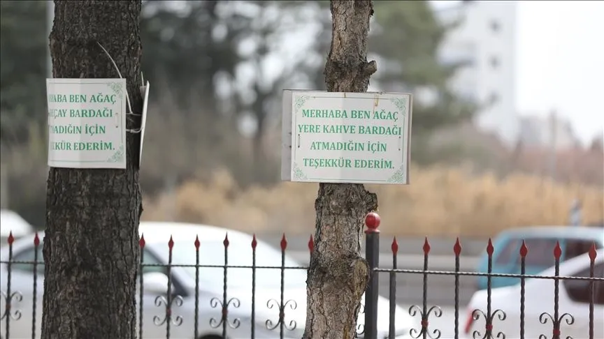 Cami bahçesindeki ağaçlara astığı levhalarla çevre duyarlılığına dikkati çekiyor